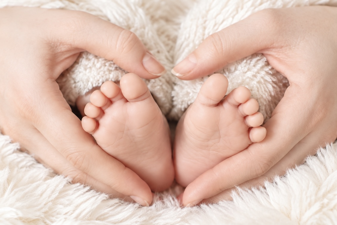 Kleine Babyfüße in den Händen der Eltern